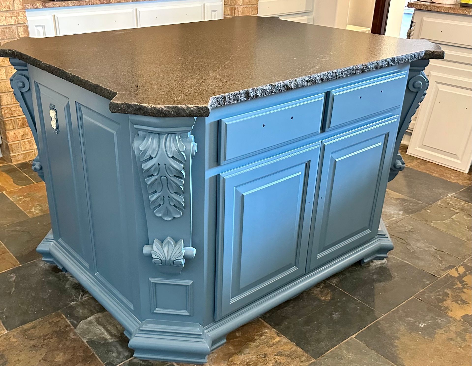 A kitchen island with blue cabinets and a granite counter top.