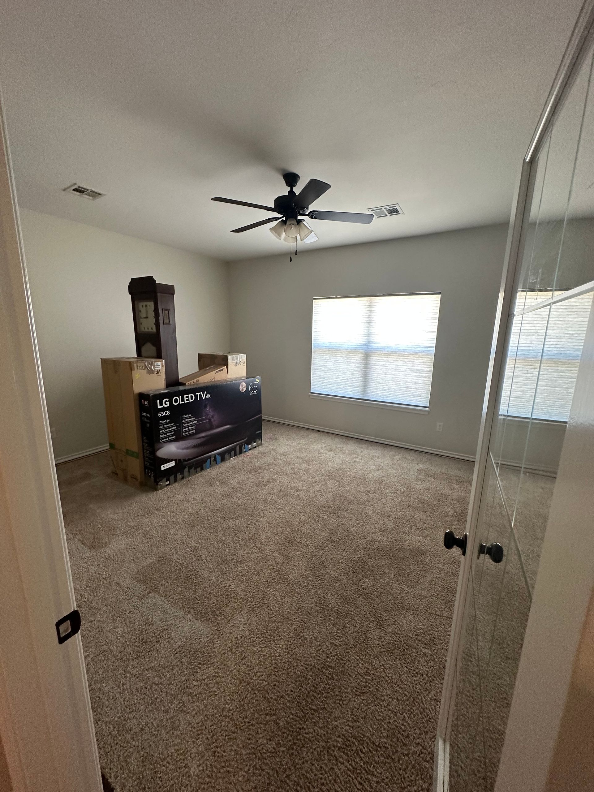 A bedroom with a ceiling fan and boxes on the floor.