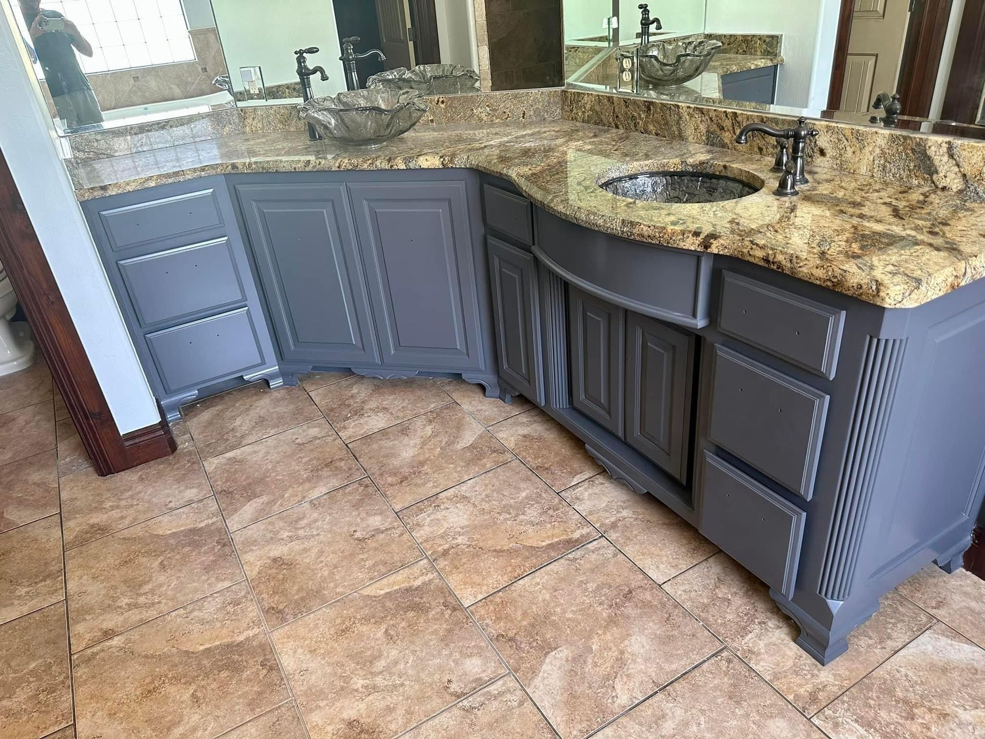 A bathroom vanity with a sink , mirror and granite counter top.