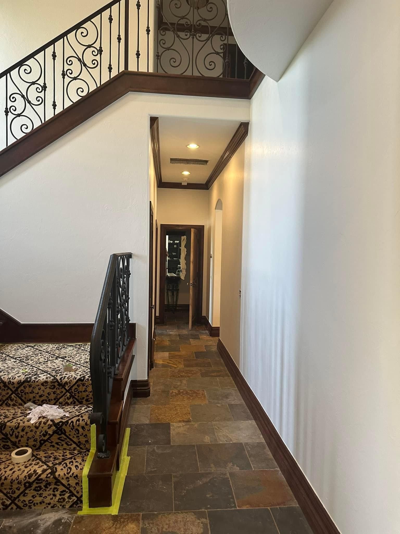 A hallway with a staircase and a wrought iron railing