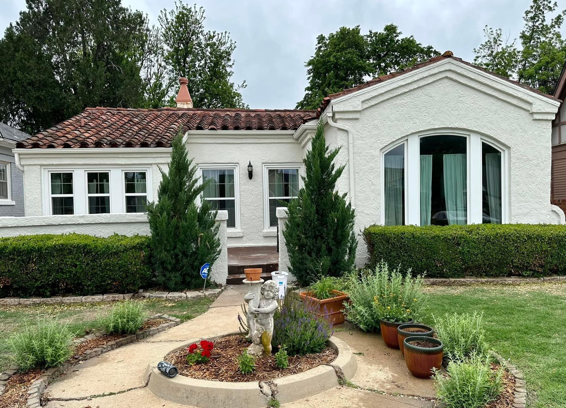 A white house with a tile roof and a garden in front of it.