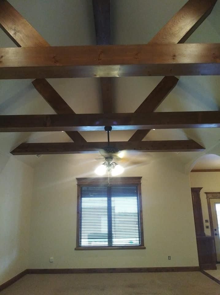 A living room with a ceiling fan and wooden beams