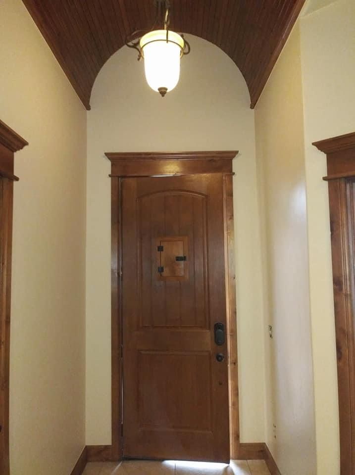A hallway with a wooden door and a light hanging from the ceiling