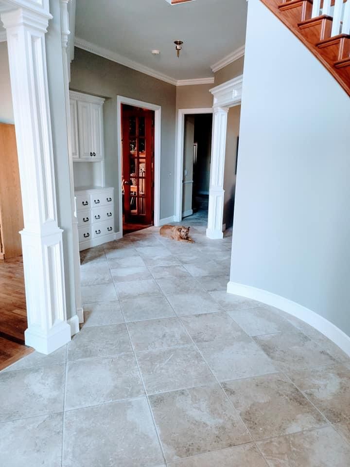 A dog is sitting in a hallway next to a staircase in a house.