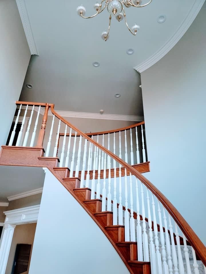 A curved staircase with white railings and a chandelier hanging from the ceiling