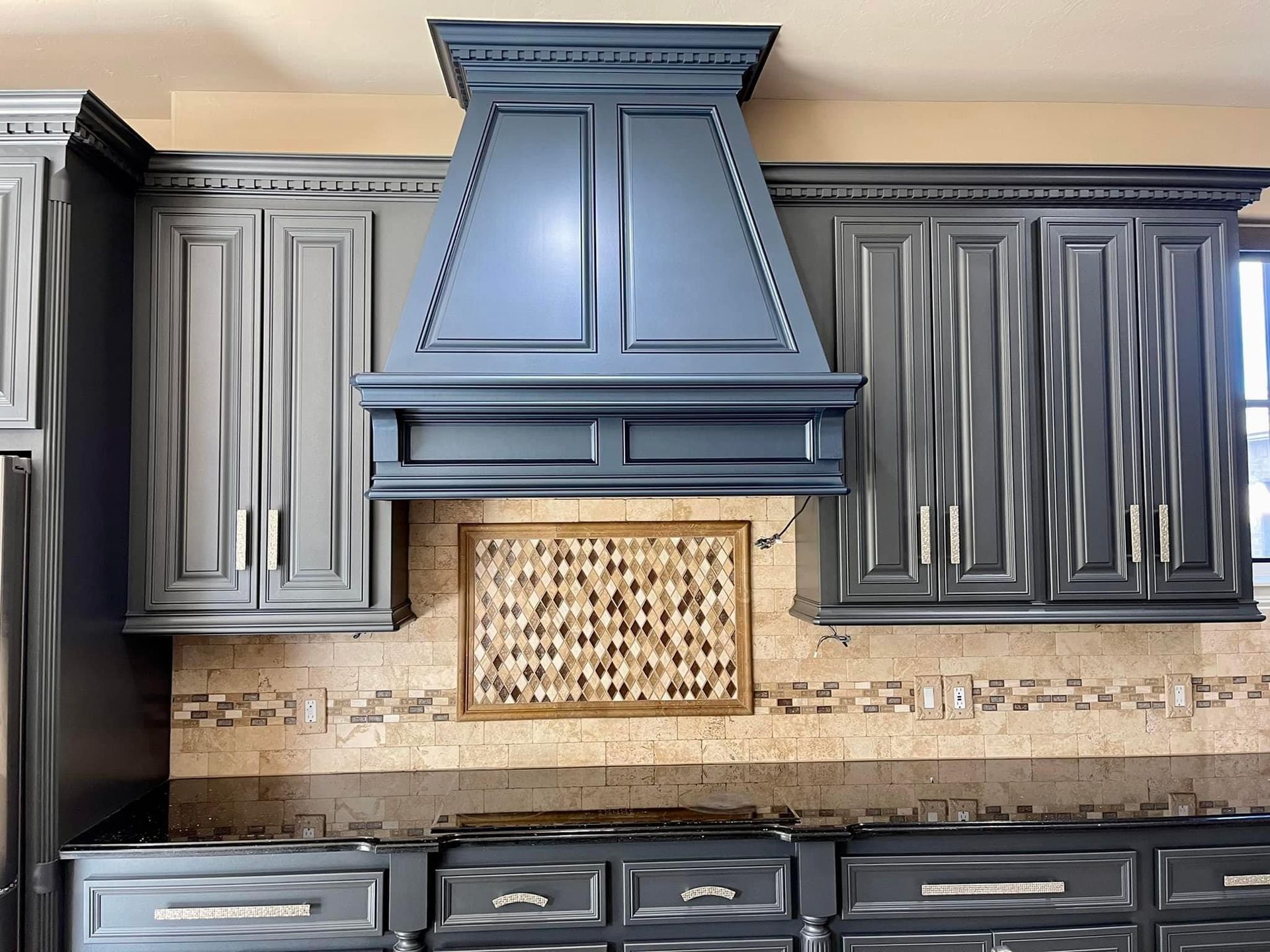 A kitchen with gray cabinets and a hood above the stove