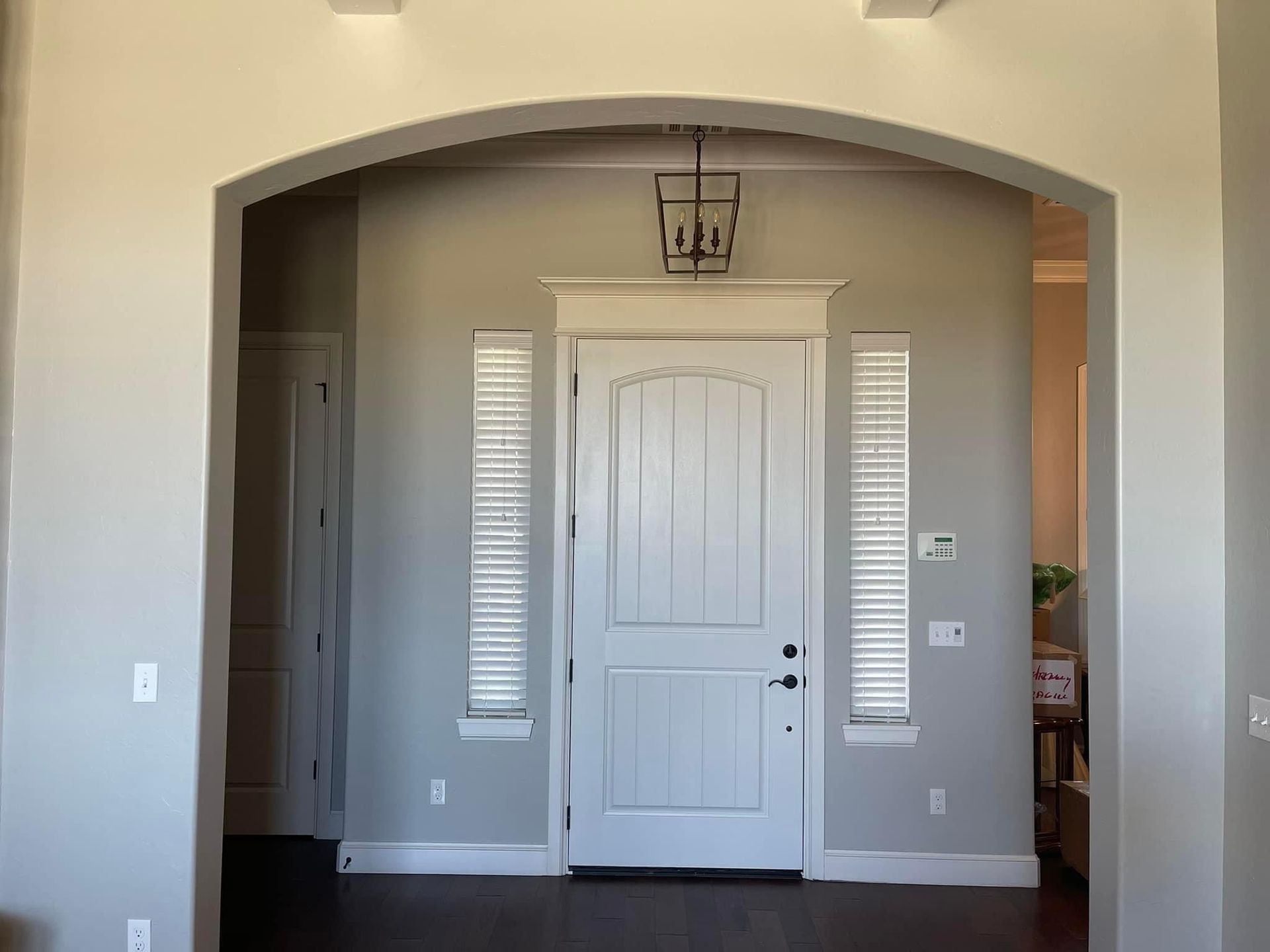 A large empty room with a white door and arched ceiling.