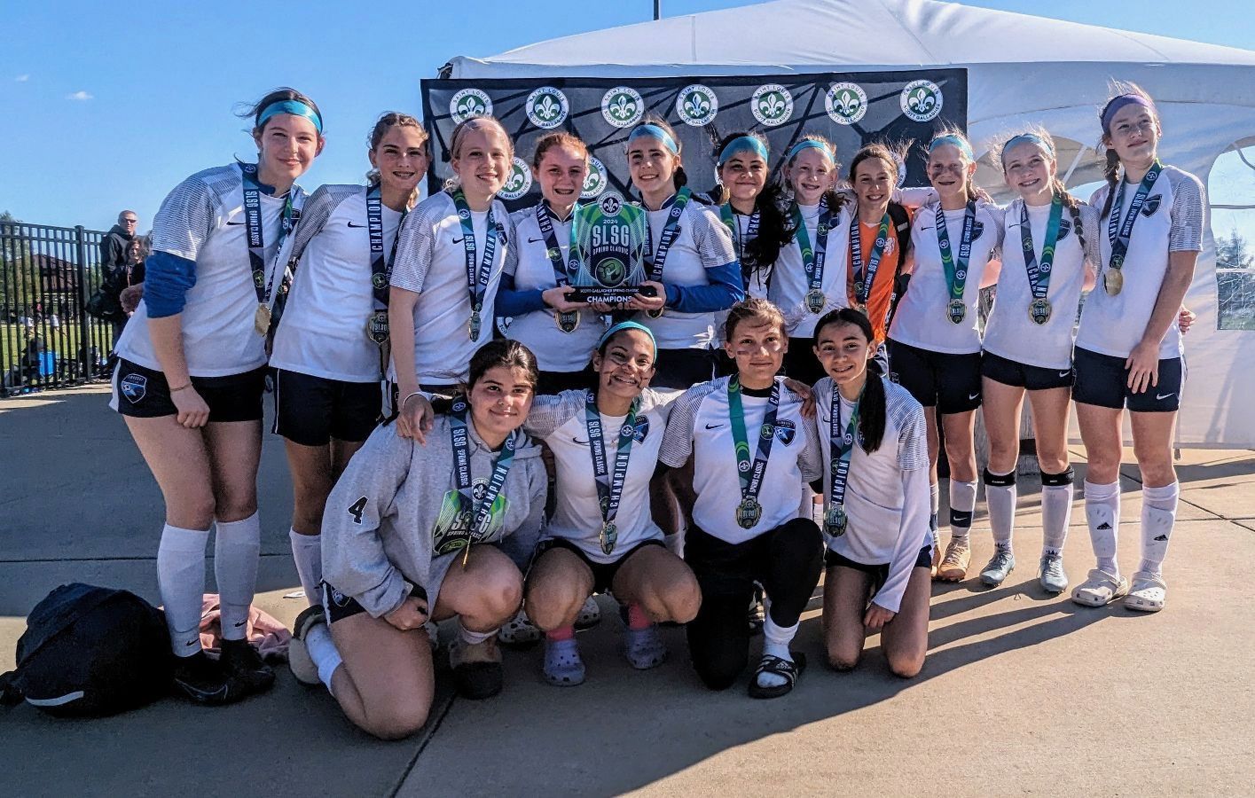 A group of young girls are posing for a picture with a trophy.