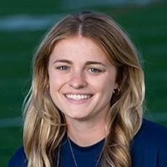 A woman in a blue shirt is smiling for the camera.