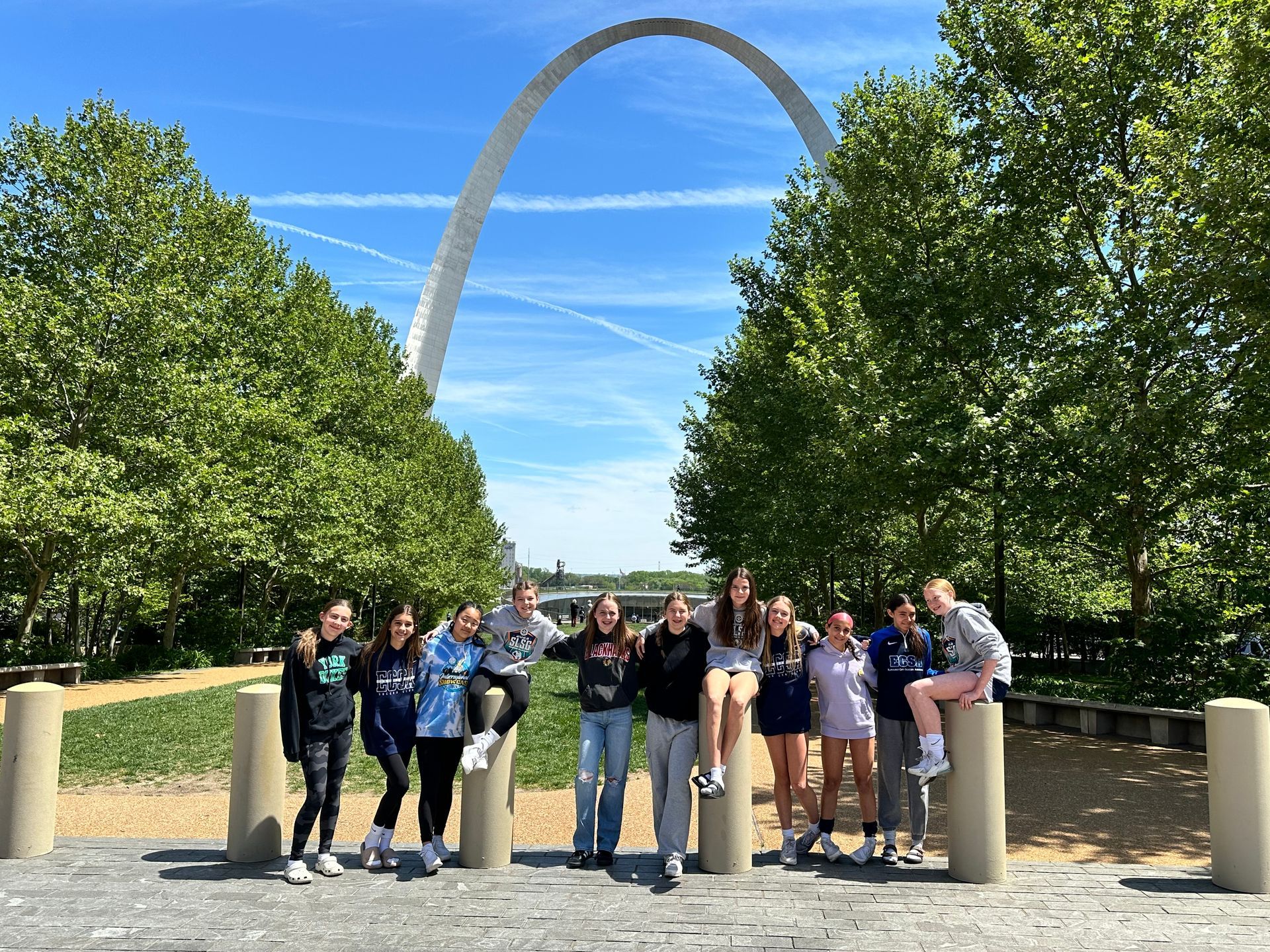 A group of people are posing for a picture in front of a large arch.