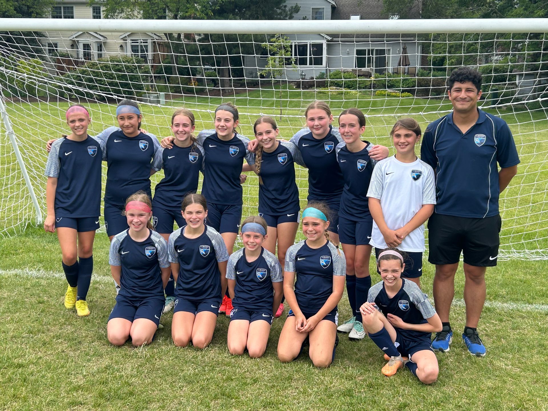 A group of young girls are posing for a picture on a soccer field.