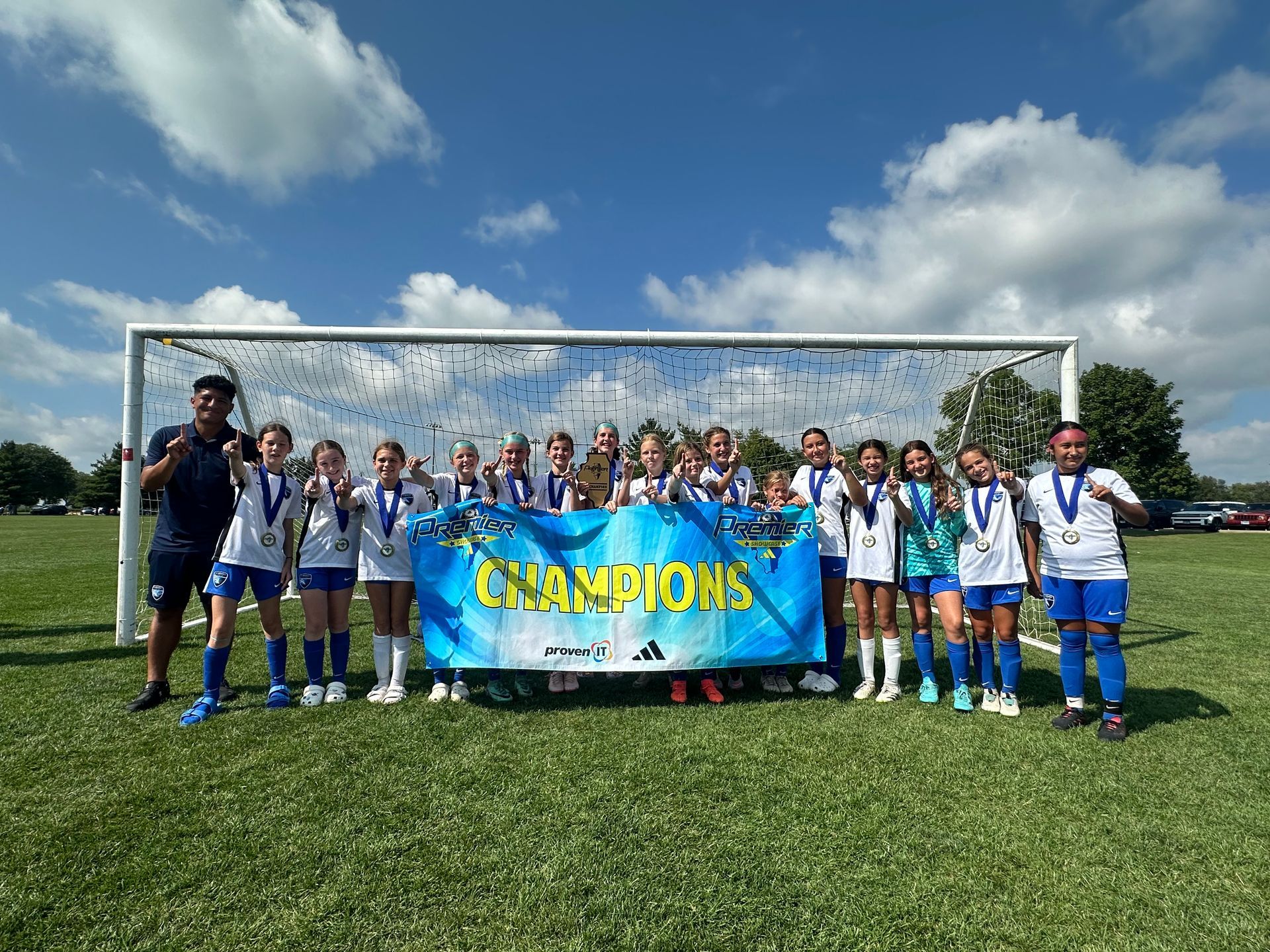 A group of young girls are posing for a picture in front of a soccer goal.