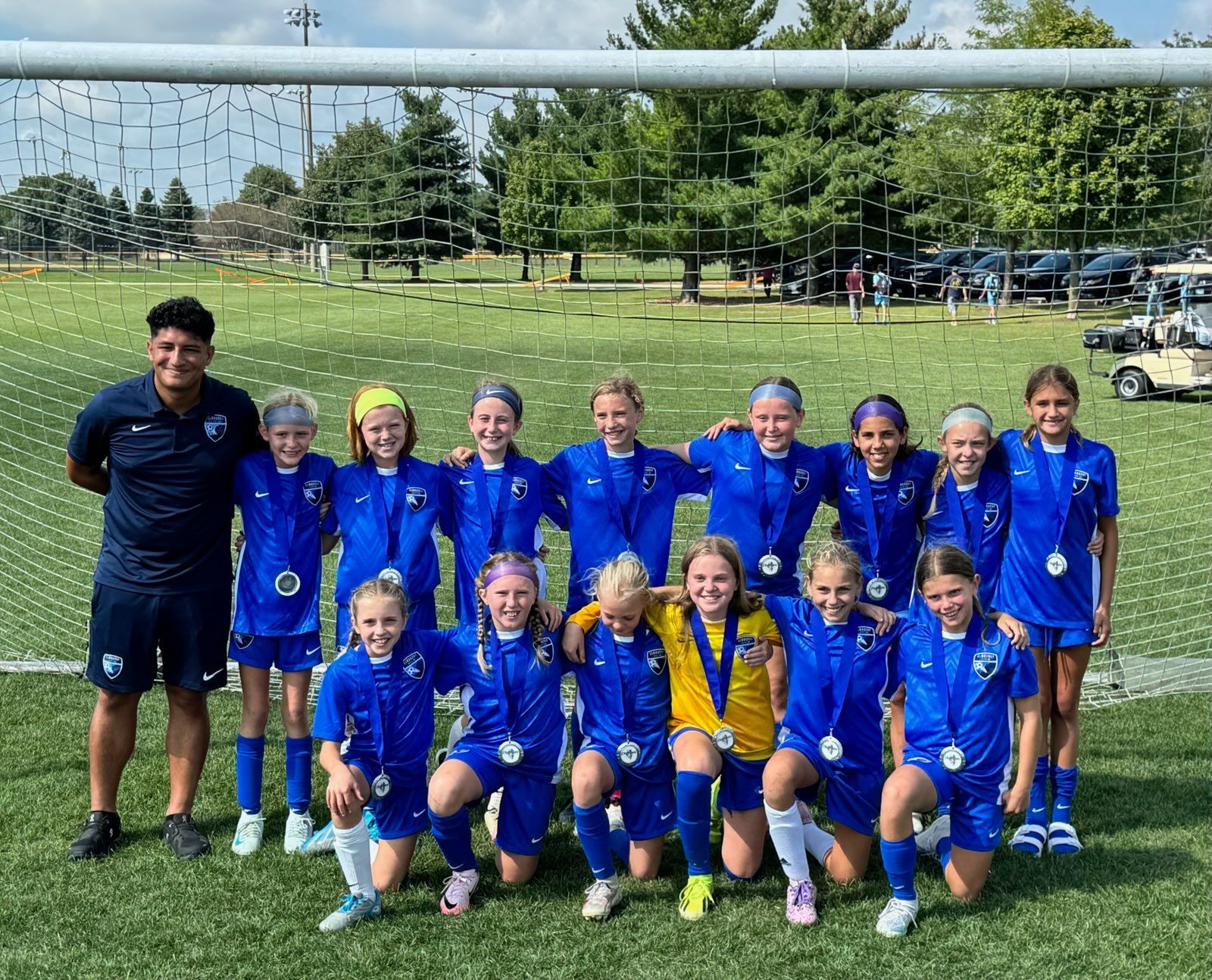 A group of young girls are posing for a picture on a soccer field.