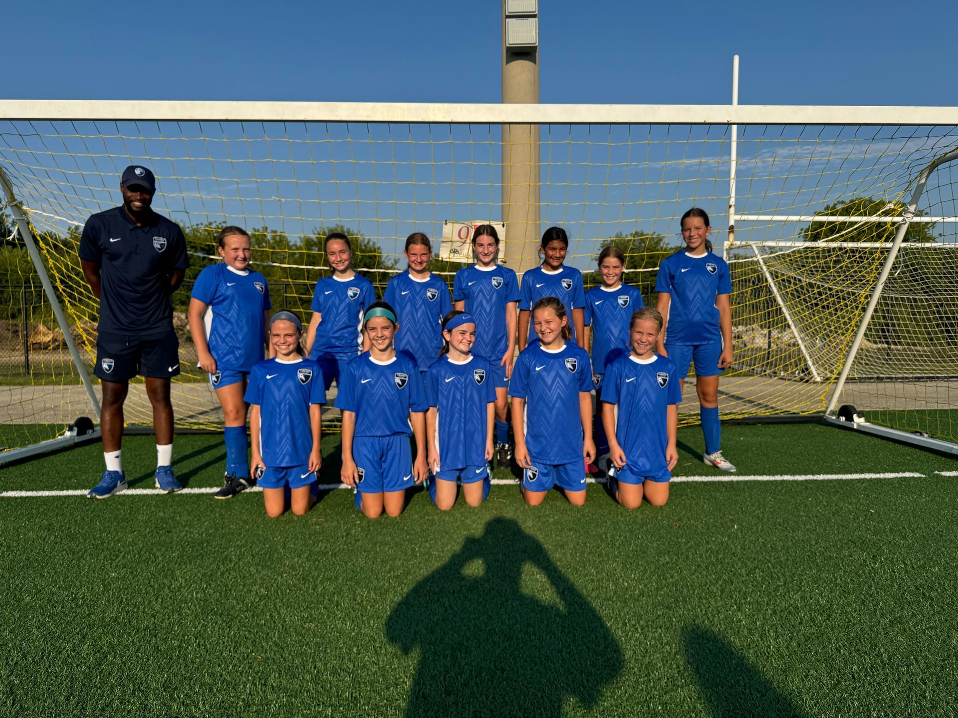 A group of young girls are posing for a picture on a soccer field.