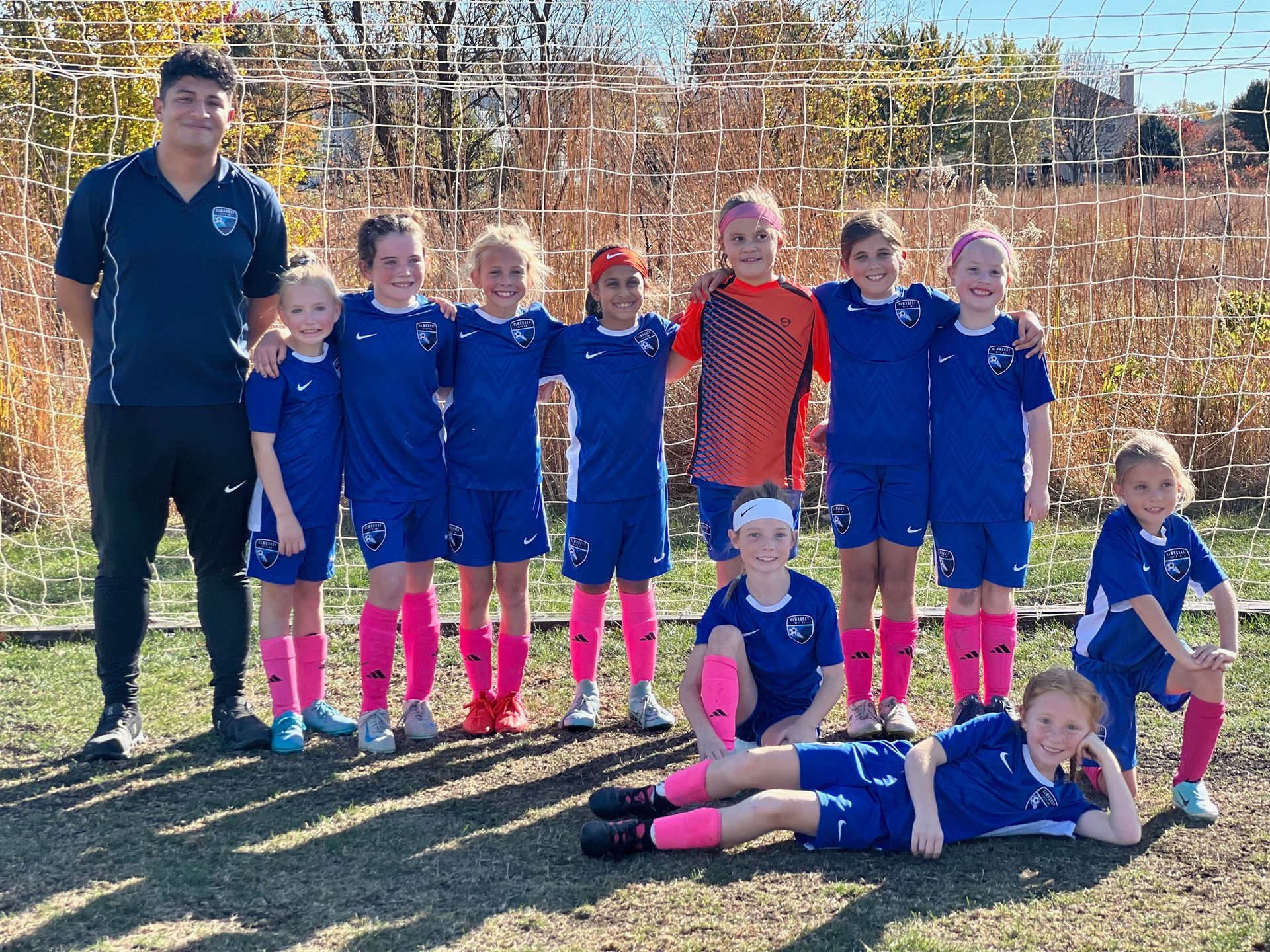 A group of young girls are posing for a picture on a soccer field.