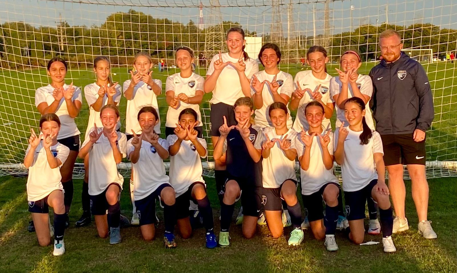 A group of young girls are posing for a picture on a soccer field.