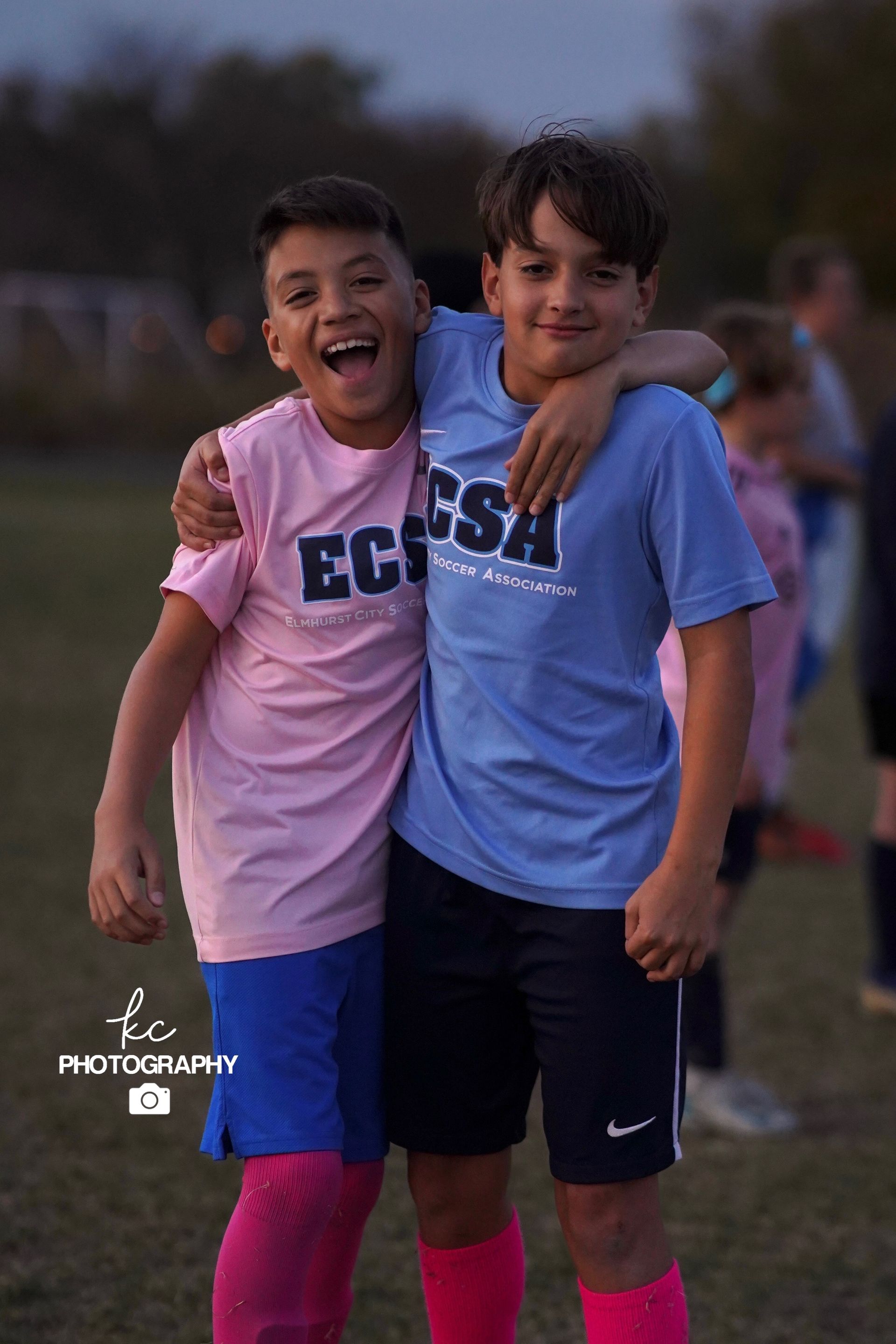 Two young boys are posing for a picture on a soccer field.