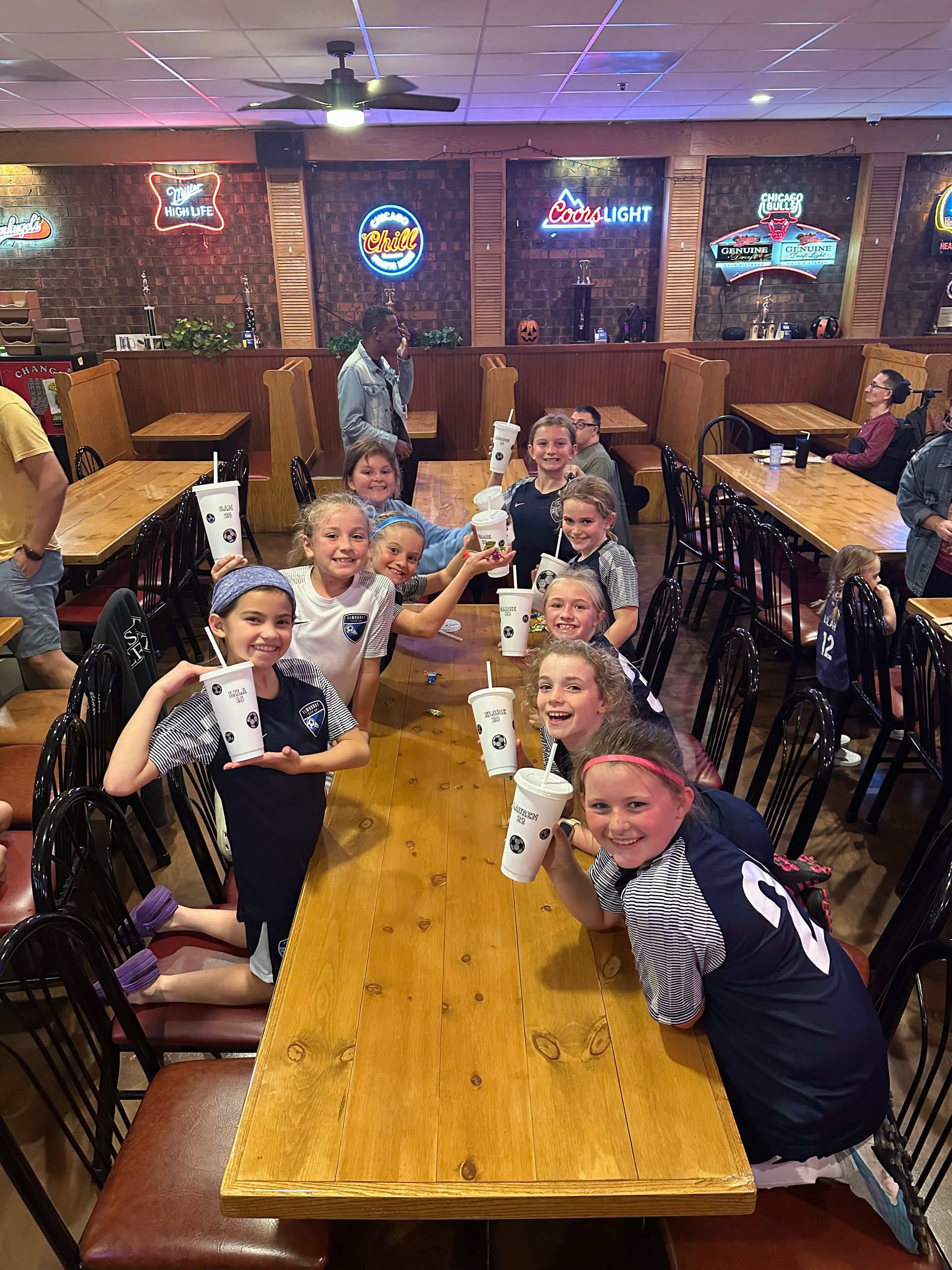 A group of children are sitting at a table in a restaurant.