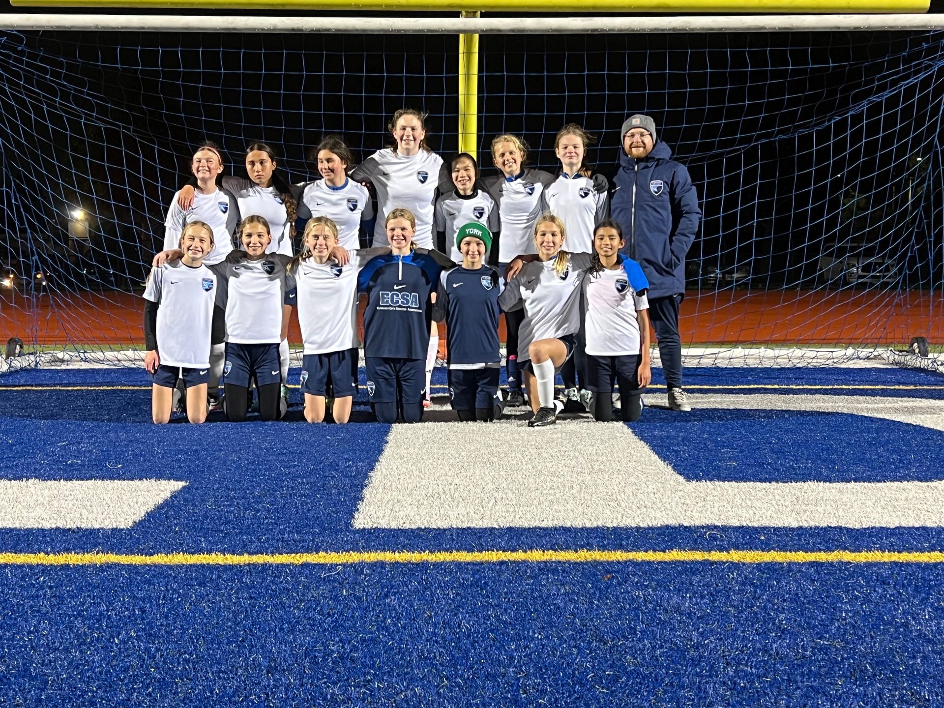 A group of young boys are posing for a picture on a soccer field.