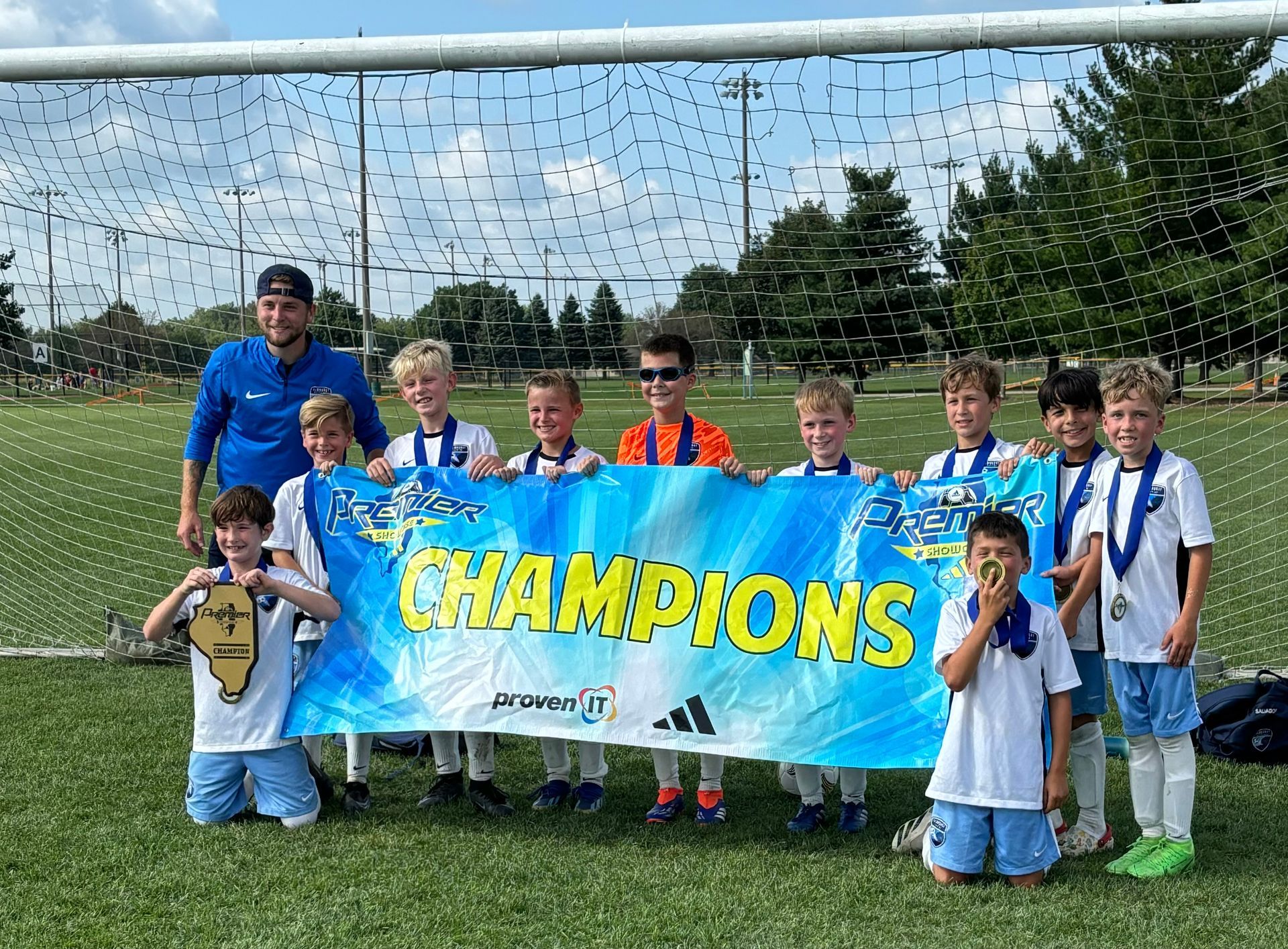 A group of young boys are holding a champions banner on a soccer field.