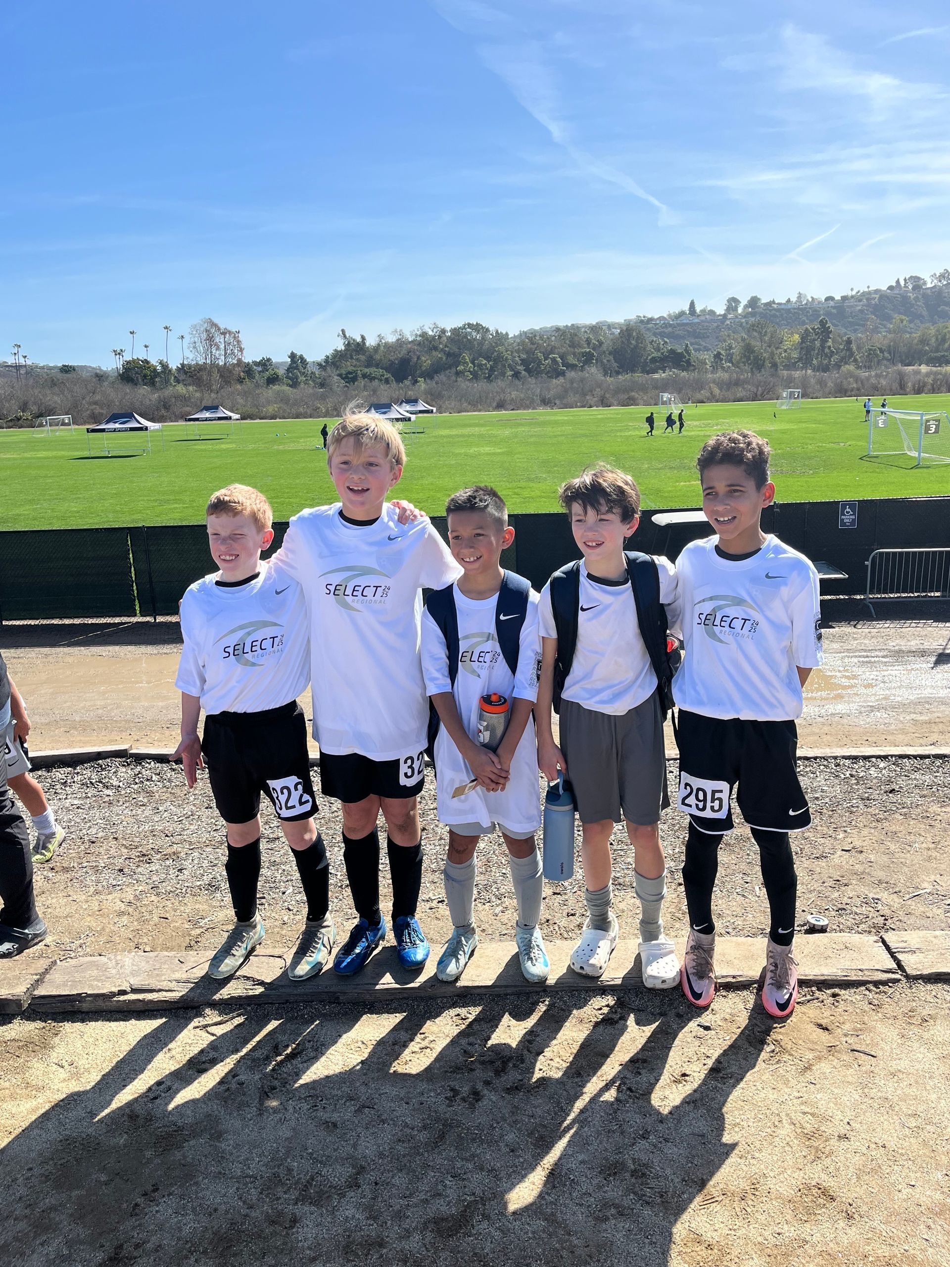 A group of young boys are posing for a picture in front of a soccer field.