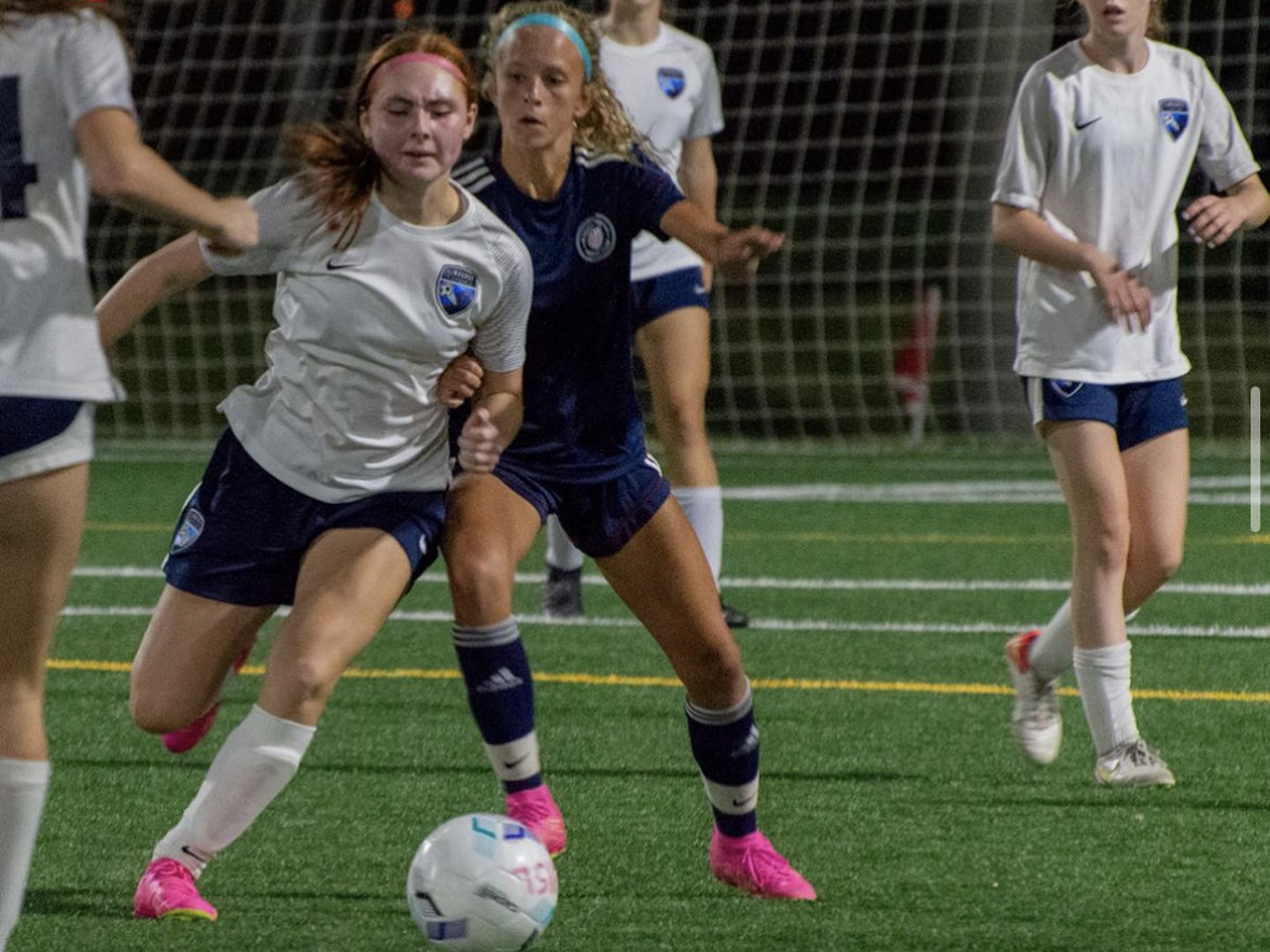 A group of young women are playing soccer on a field.