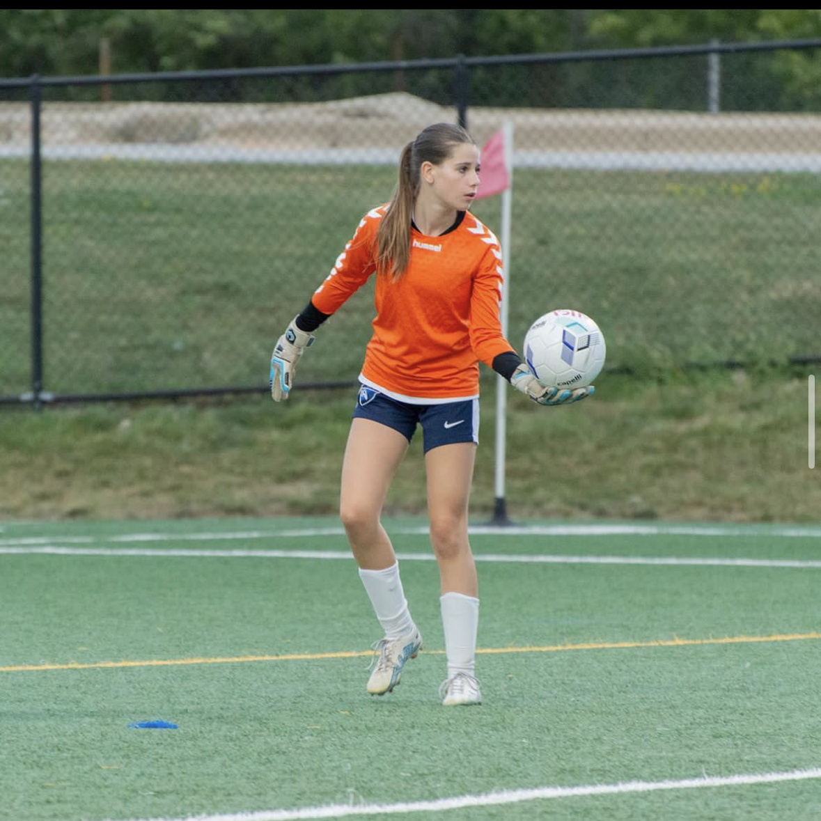 A girl holding a soccer ball with the number 2 on it