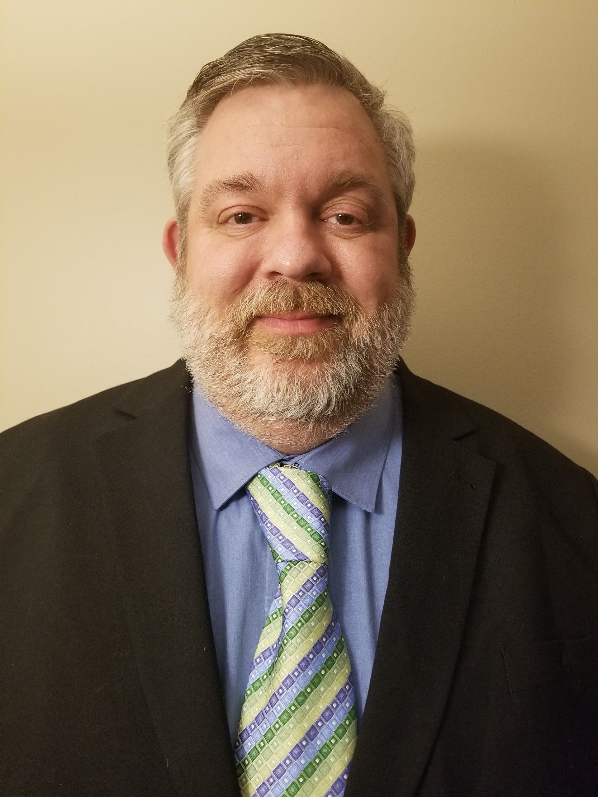 A man with a beard is wearing a suit and tie.