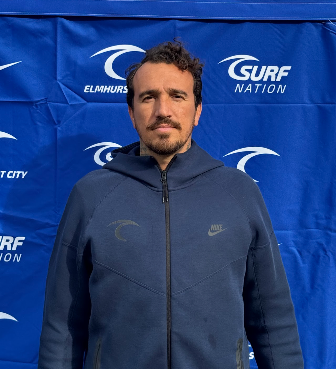 A man with a tattoo on his neck is wearing a blue shirt.