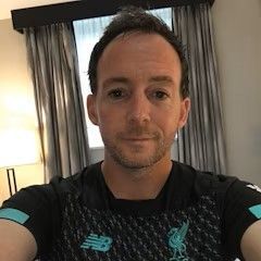 A man with a beard is taking a selfie in a hotel room.