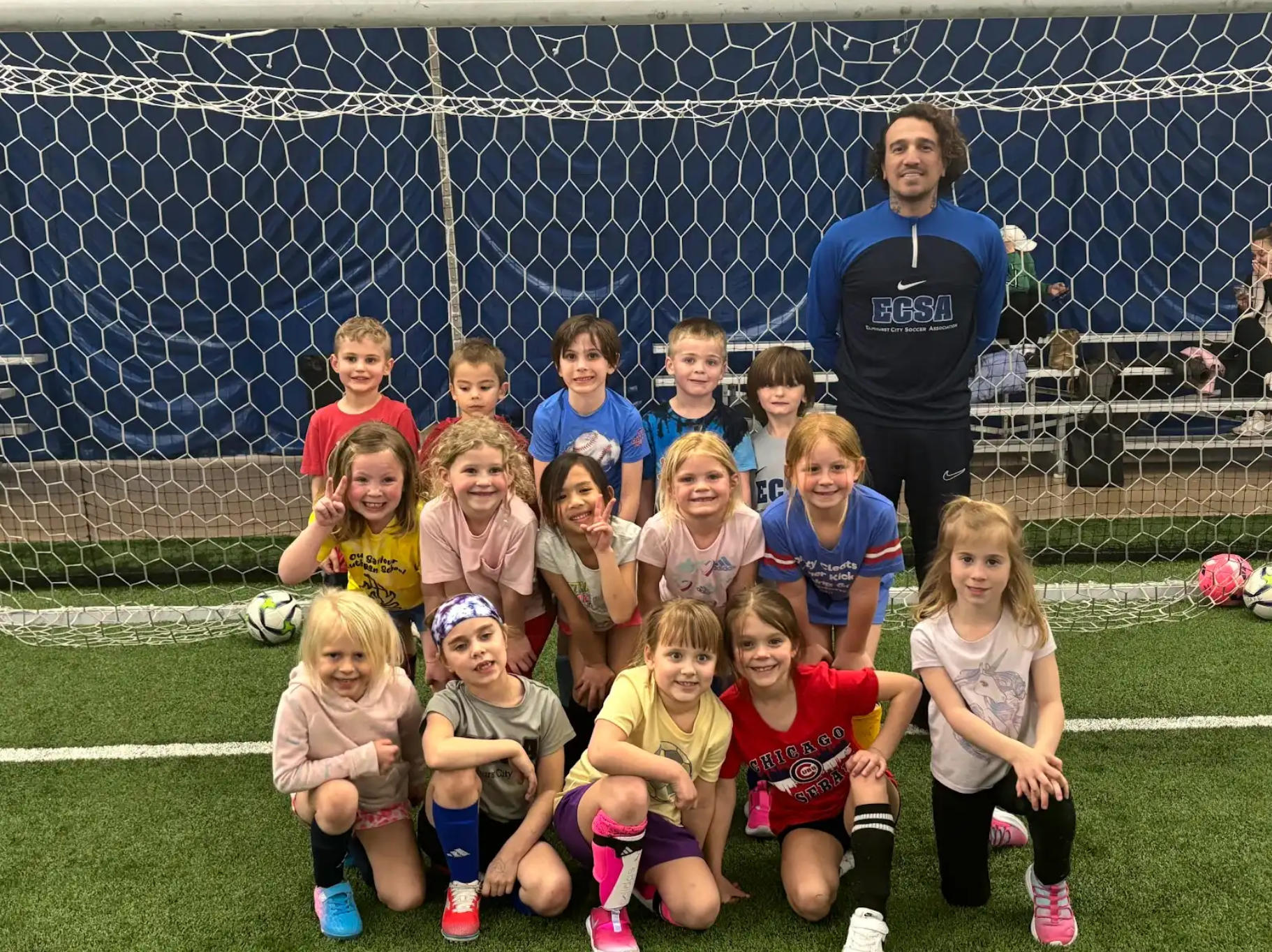 A group of young children are posing for a picture on a soccer field.