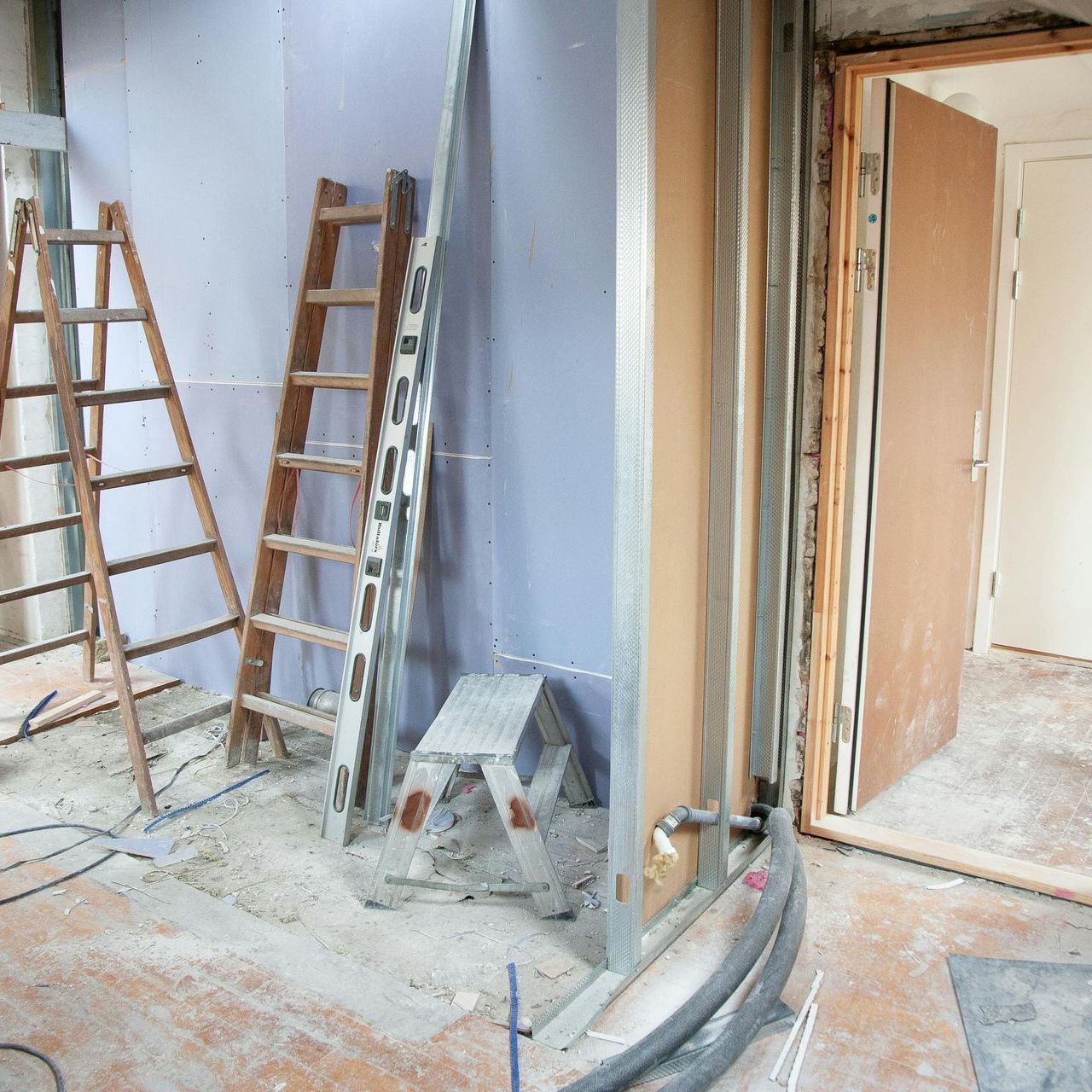 A wooden ladder is leaning against a wall in a room under construction