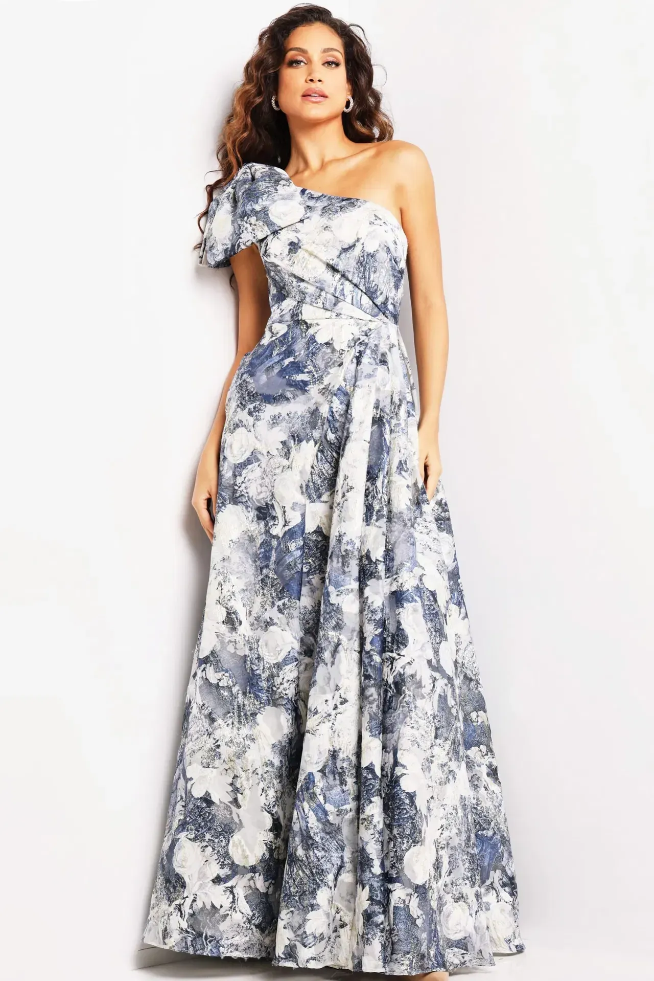 A woman is wearing a blue and white floral one shoulder dress.