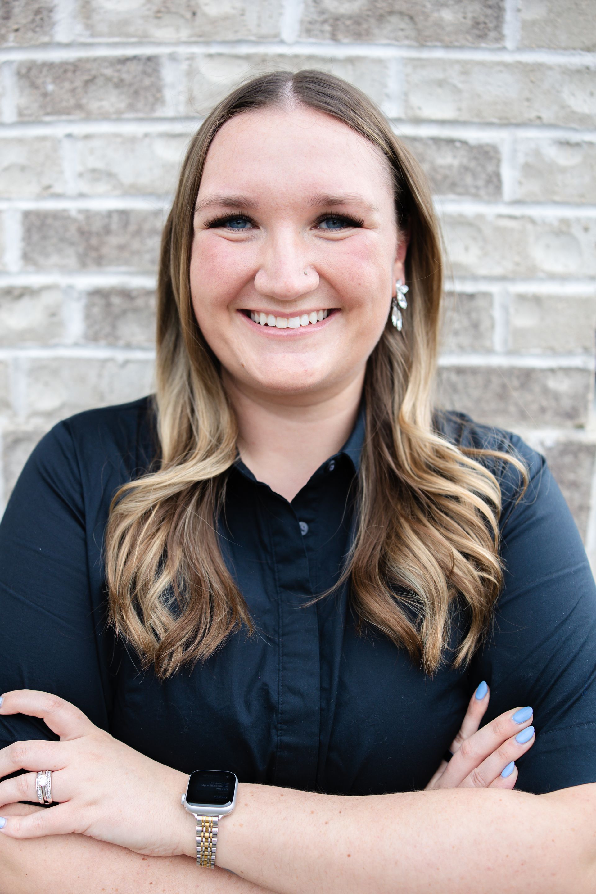 A woman wearing glasses and a floral shirt is touching her face.