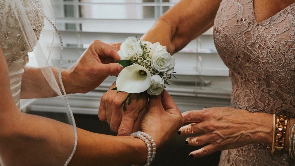 A woman is putting a flower on a woman 's wrist.