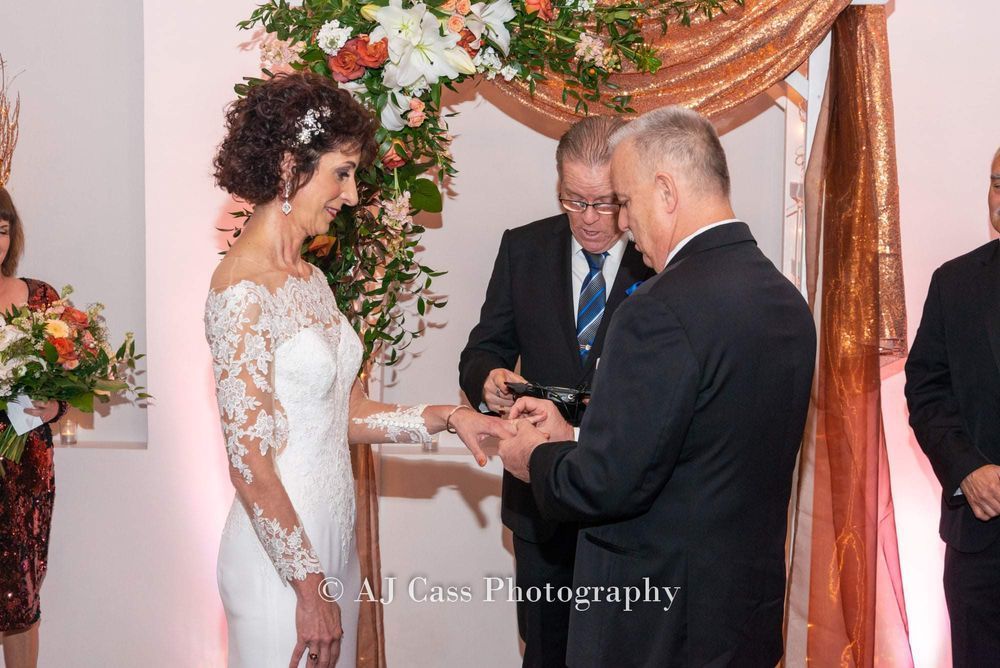 A man is putting a ring on a woman 's finger during a wedding ceremony.