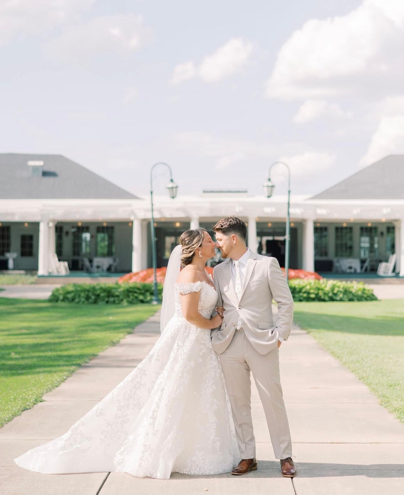 A bride and groom are standing next to each other on a sidewalk in front of a building.
