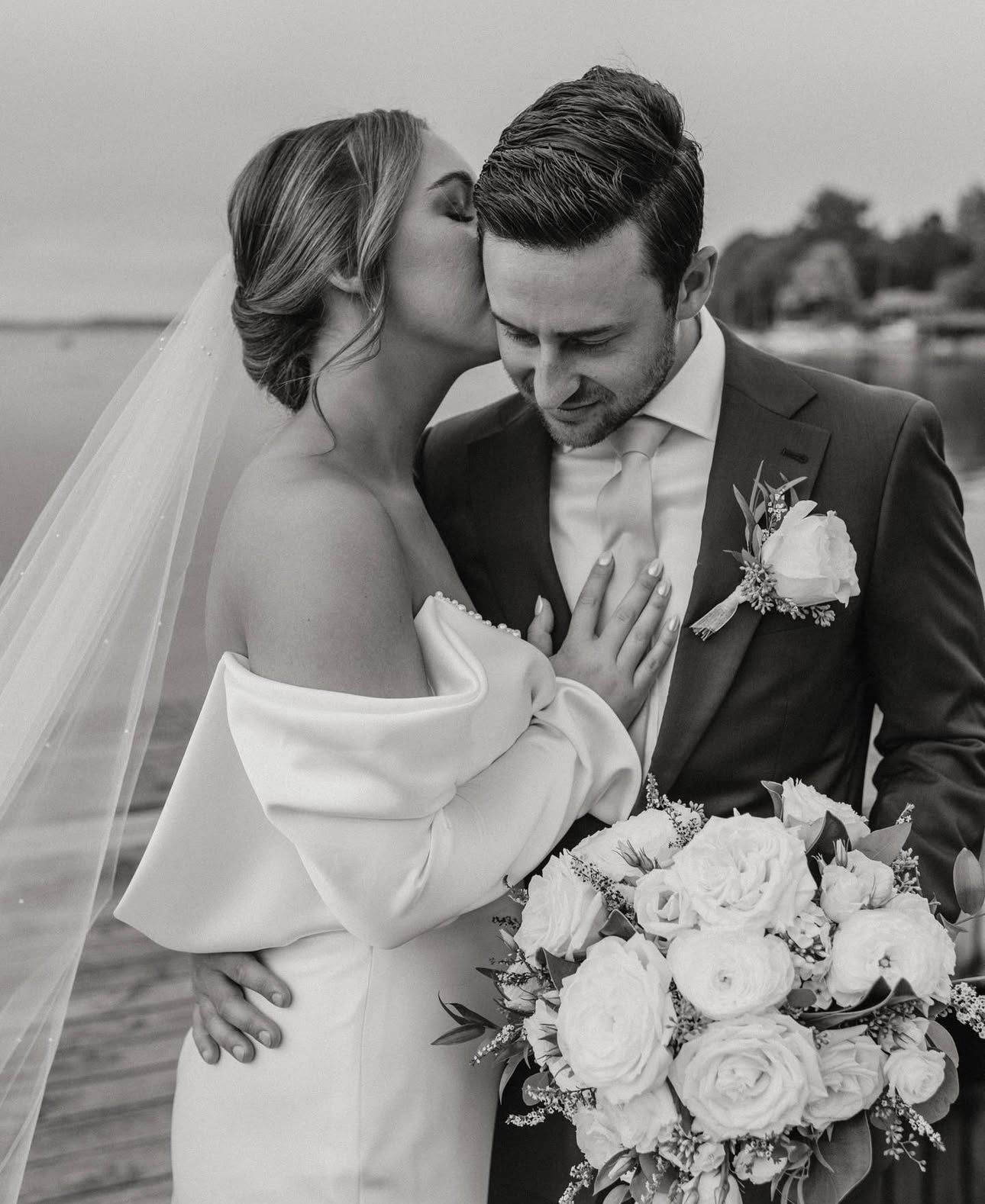 A bride and groom are kissing in a black and white photo.