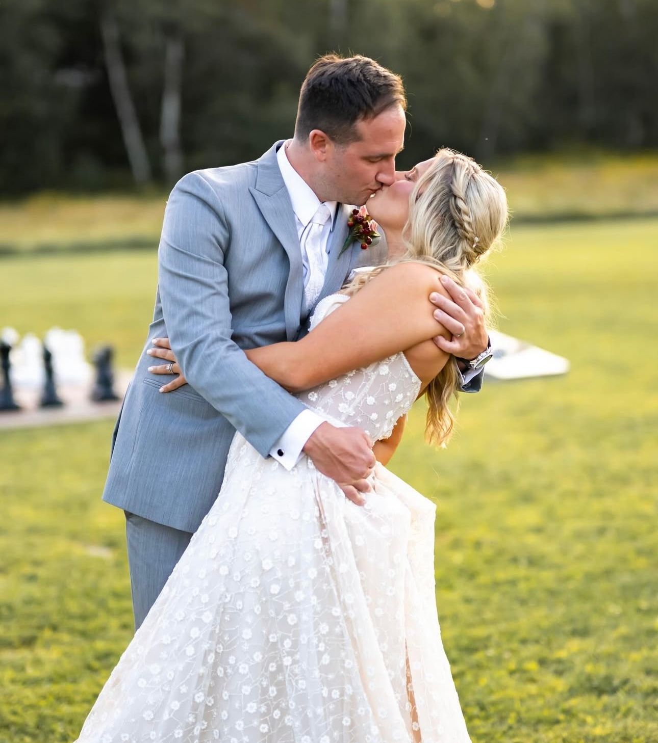A bride and groom kissing in a field with chess pieces in the background.