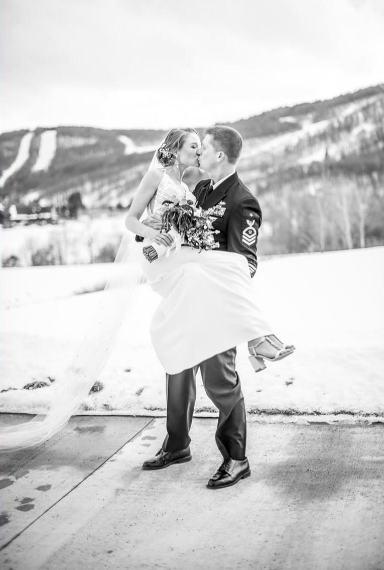 A bride and groom are kissing in the snow in a black and white photo.