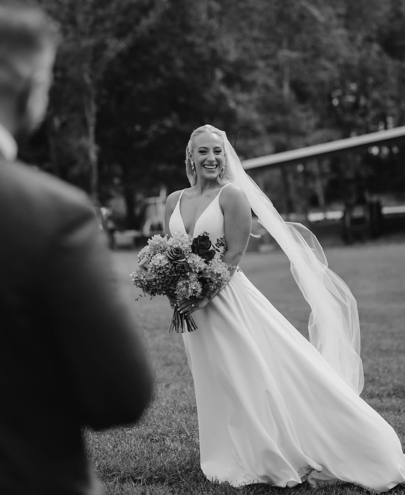 A black and white photo of a bride in a wedding dress holding a bouquet of flowers.