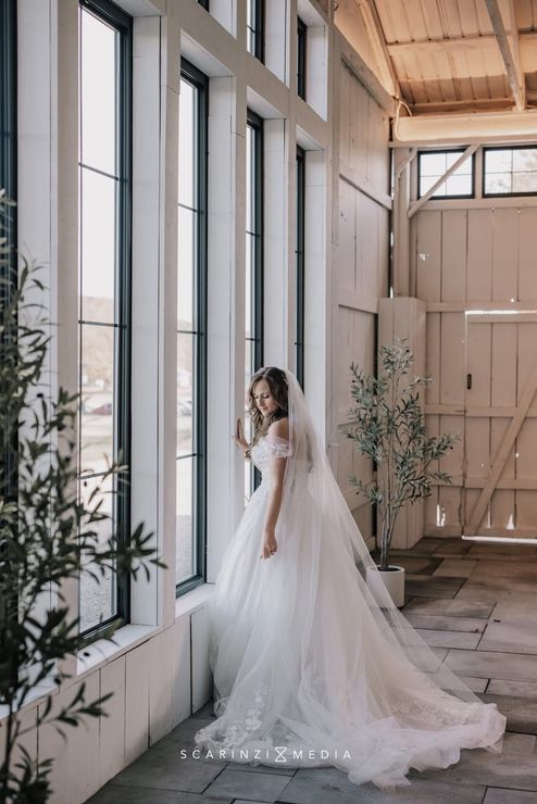A woman in a white wedding dress is standing in front of a mountain.