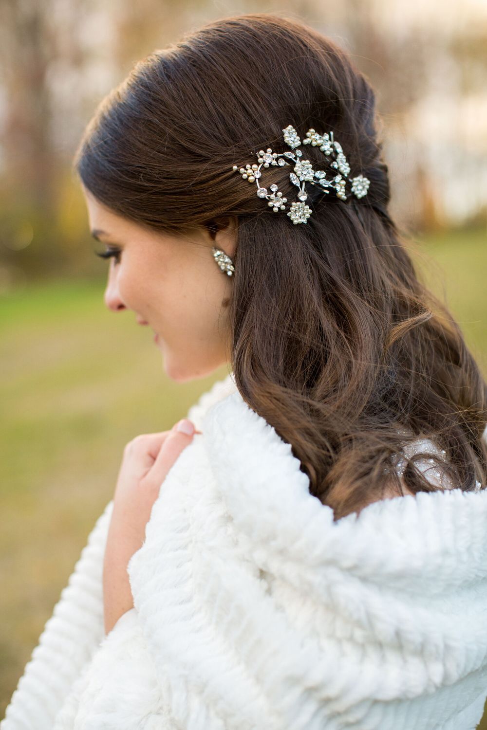A woman wearing a white fur coat and a hair clip in her hair.