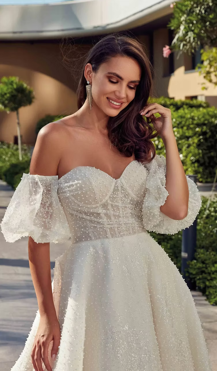 A woman is wearing a white wedding dress with puffed sleeves.