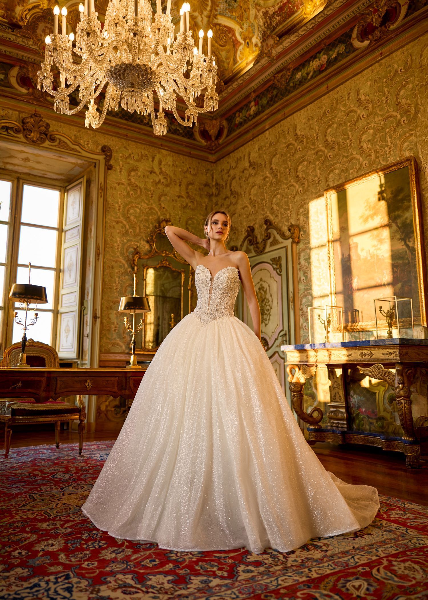 A woman in a wedding dress is standing in a room with a chandelier.