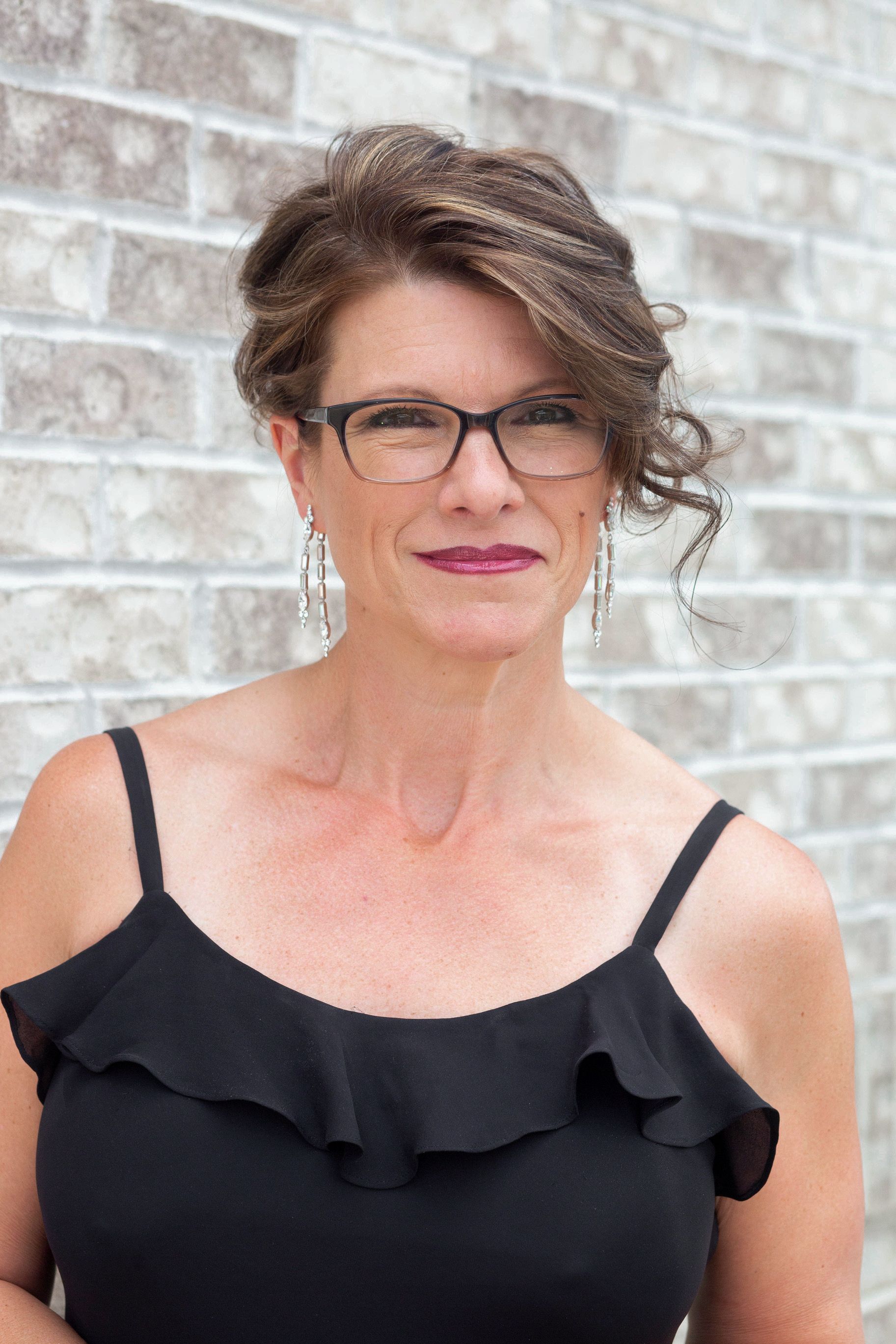 A woman is sitting on the floor with her legs crossed and smiling.