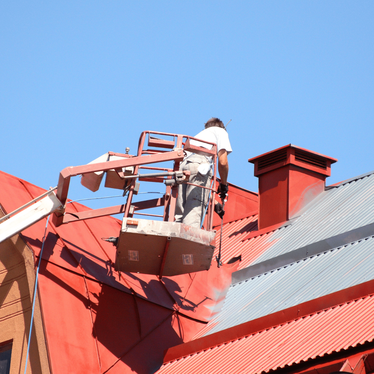 Worker painting a metal roof