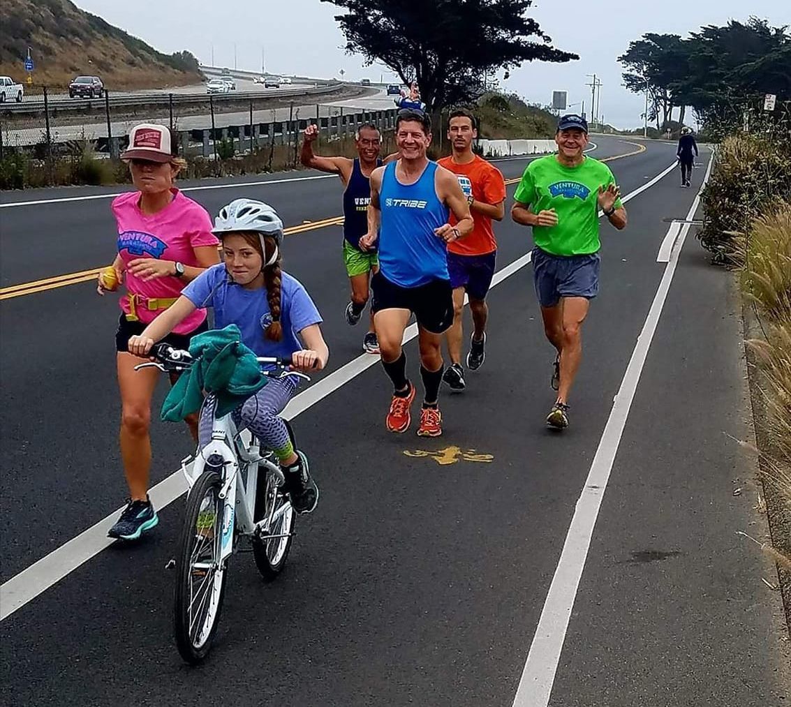 A group of people are running and riding bikes on a road