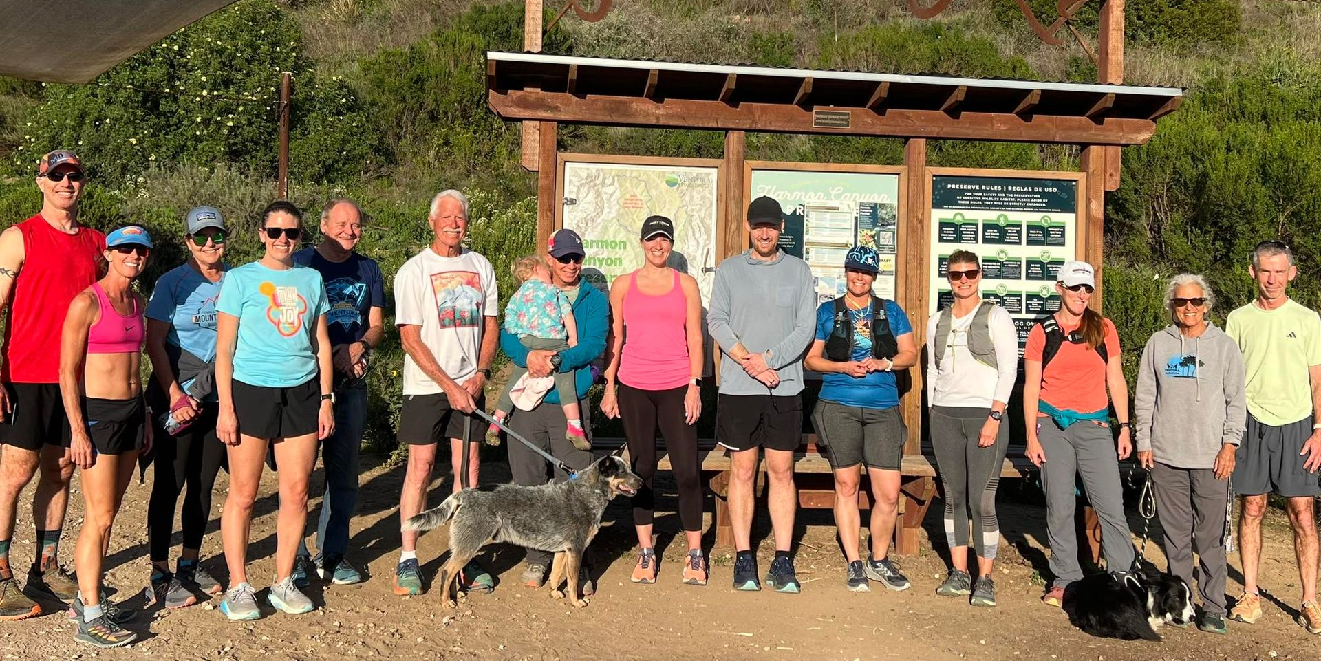 A group of people are posing for a picture in front of a large rock.