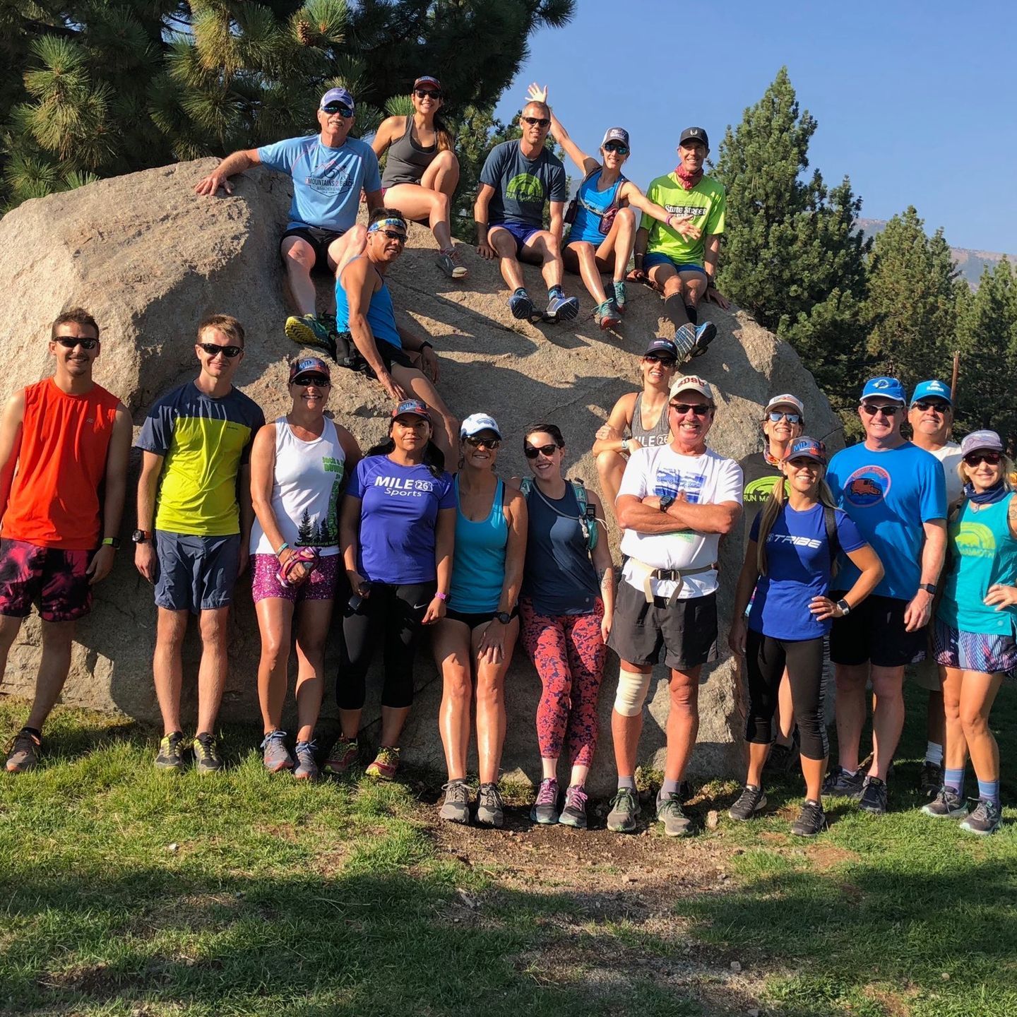 A group of people are posing for a picture in front of a large rock.